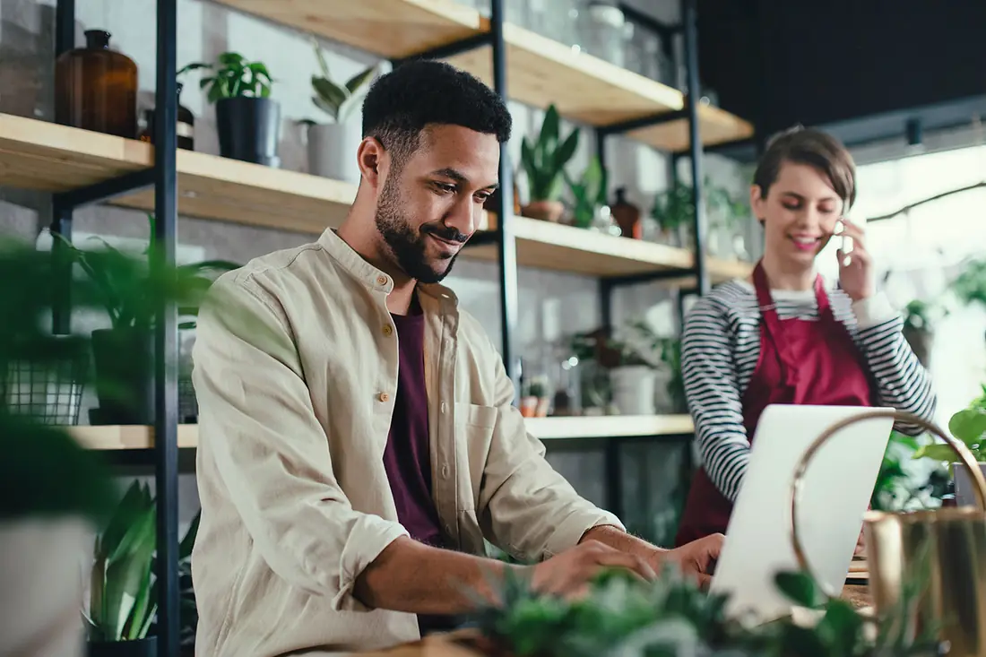 Two owners of a plant shop reading one laptop together, the way offers should be read.