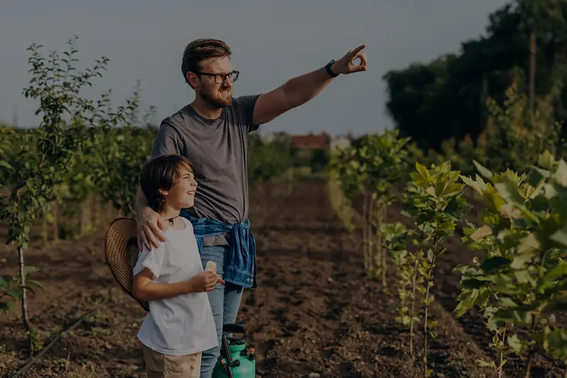 A father and son in a young orchard: a long job, paid for over the years it takes.