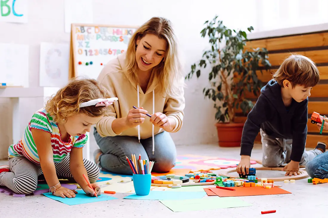 A childcare owner on the floor with the children: back to the work the money is for.